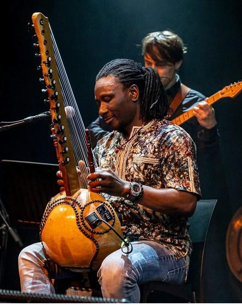 Moussa Dembélé performing on stage with Yelemani Trio